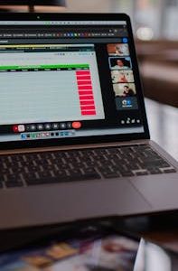 Laptop displaying a remote video meeting in a modern office setting.
