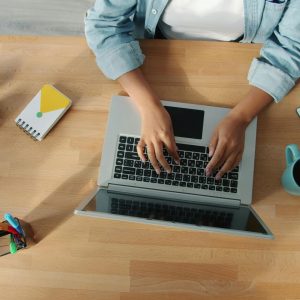 Top-down view of a person working on a laptop at a neat desk with accessories.