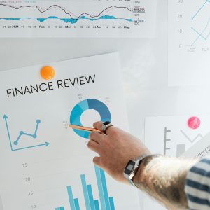 Hand pointing at a financial chart on a wall, illustrating data analysis and review.