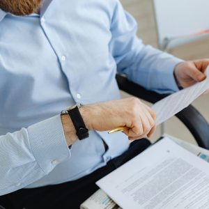Businessman reviewing papers in office setting, highlighting analysis and attention to detail.
